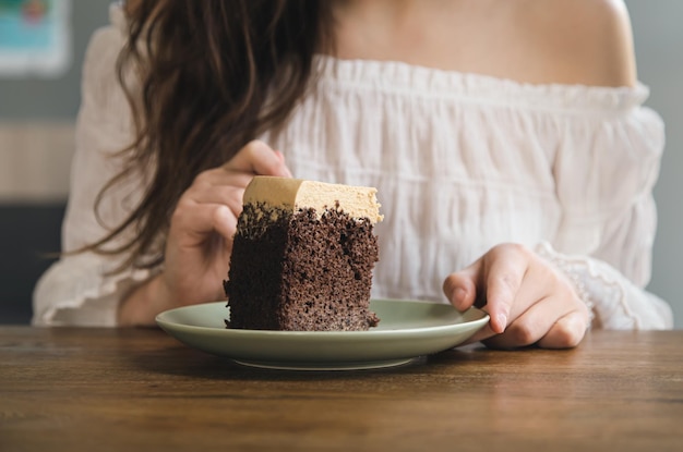 A woman eats a piece of chocolate cake closeup