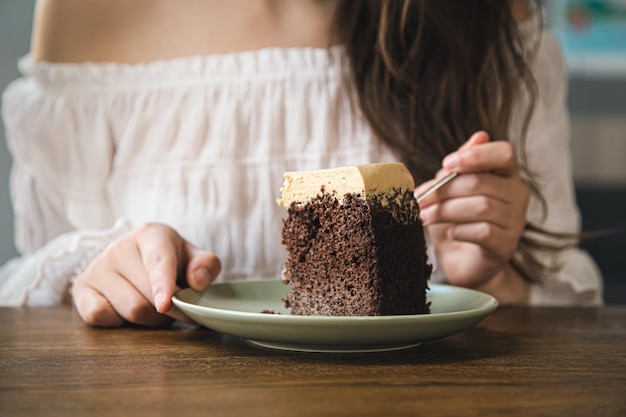 Foto gratuita una donna mangia un pezzo di torta al cioccolato primo piano