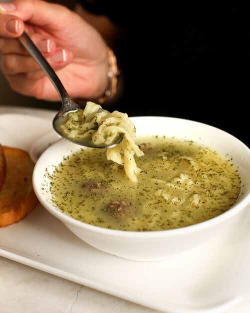 Woman eats soup served with dry herbs