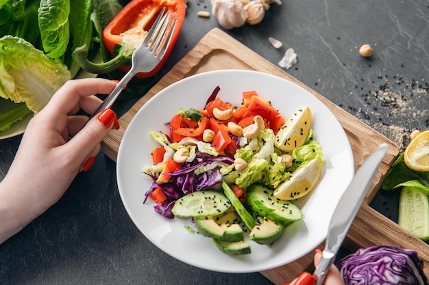 A woman eats a vegetarian salad of fresh vegetables closeup of the plate