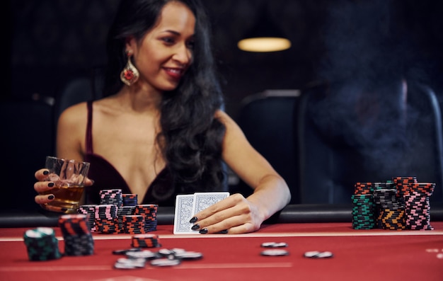 Premium Photo | Woman in elegant clothes sits in cassino by table and plays  poker game