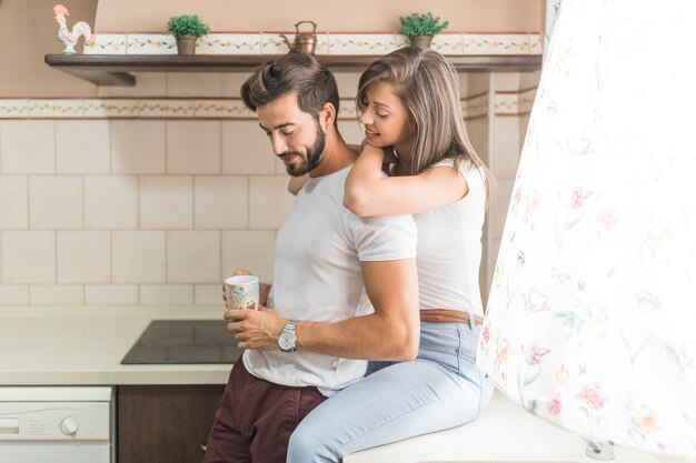 Woman embracing boyfriend with mug