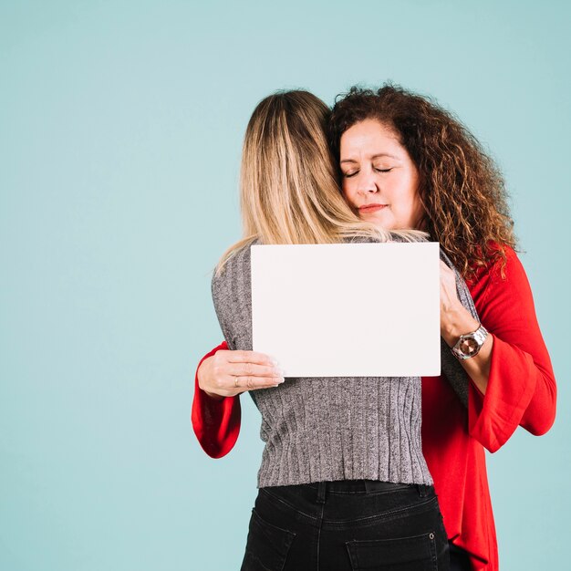 Woman embracing daughter and holding paper sheet