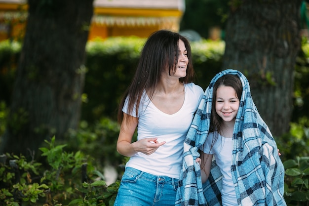 Woman embracing girl wearing plaid outside