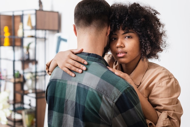 Woman embracing her boyfriend and looking at photographer