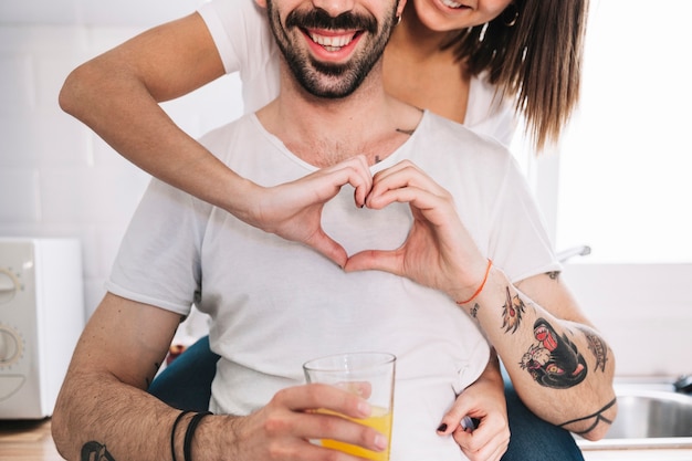 Free photo woman embracing man and showing heart gesture
