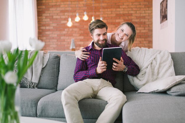 Woman embracing man using tablet