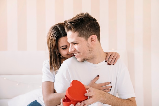 Woman embracing man with heart-shaped box