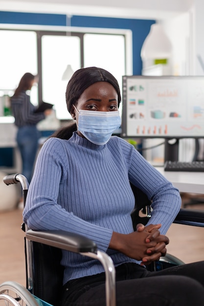 Woman employee with disabilities with protection mask against coronavirus looking at front