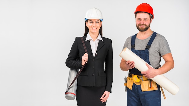 Женщина инженер и строитель, стоя с улыбкой Ватмана