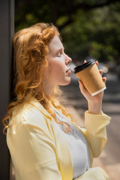 無料写真 屋外で一杯のコーヒーを楽しんでいる女性