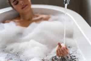 Бесплатное фото Женщина, наслаждаясь расслабляющей пенной ванной