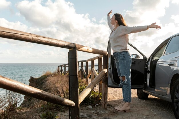 車の隣でビーチのそよ風を楽しんでいる女性