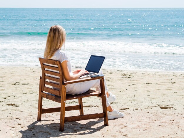 노트북에서 작업하는 동안 해변을 즐기는 여자