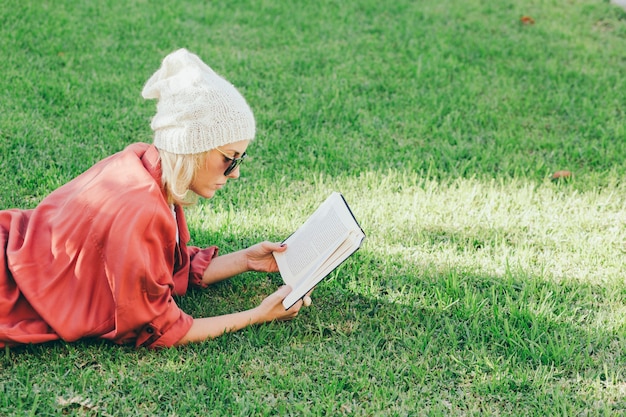 Женщина, наслаждаясь книгой на траве