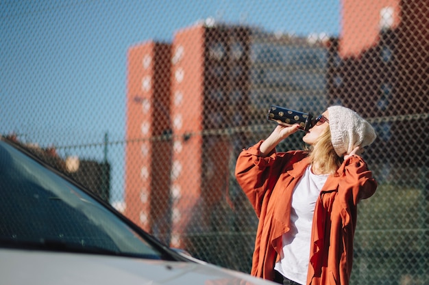 車の近くでコーヒーを楽しむ女性