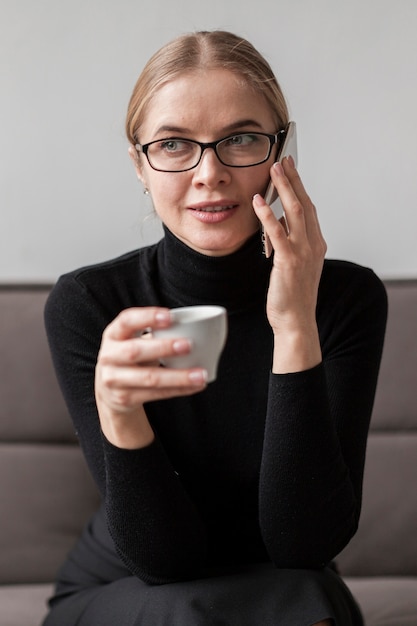 Foto gratuita donna che gode del caffè e che parla sopra il telefono