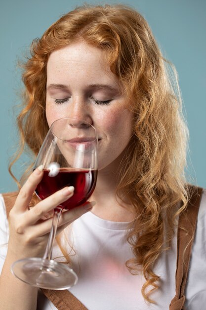 Женщина, наслаждаясь бокалом красного вина
