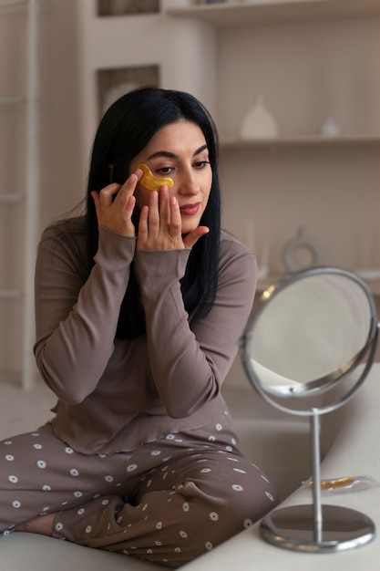 Free photo woman enjoying her beauty routine with golden eye patches