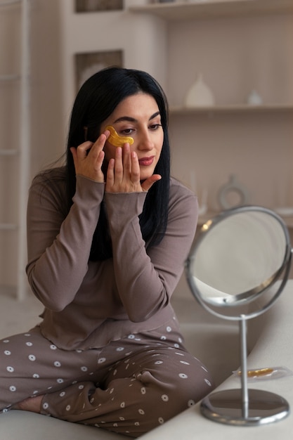 Woman enjoying her beauty routine with golden eye patches