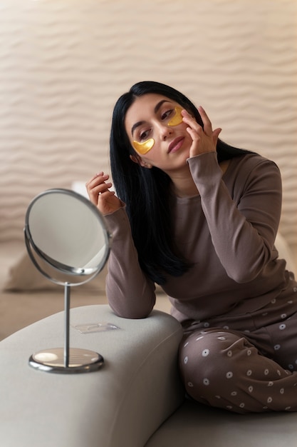 Woman enjoying her beauty routine with golden eye patches