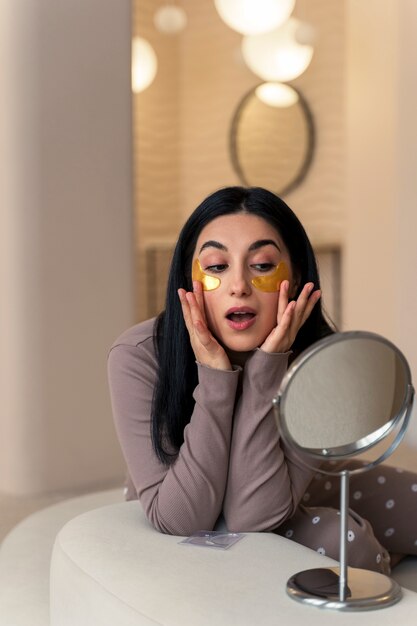 Woman enjoying her beauty routine with golden eye patches