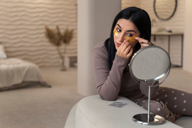 Woman enjoying her beauty routine with golden eye patches