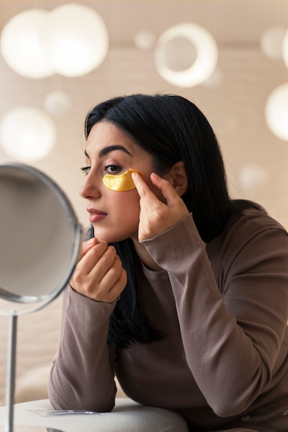 Woman enjoying her beauty routine with golden eye patches