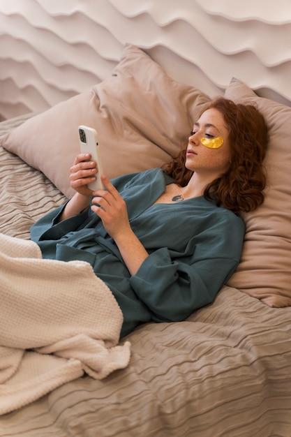 Free photo woman enjoying her beauty routine with golden eye patches