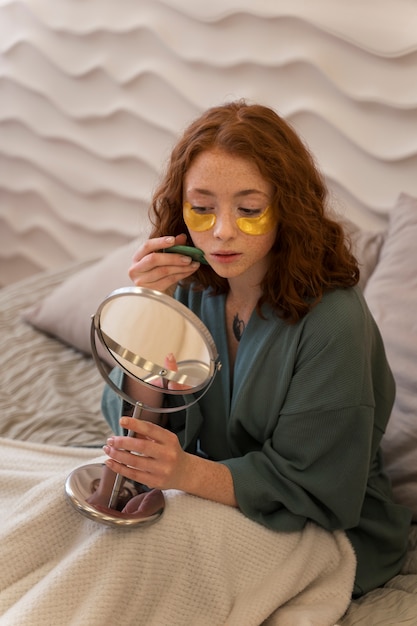 Free photo woman enjoying her beauty routine with golden eye patches