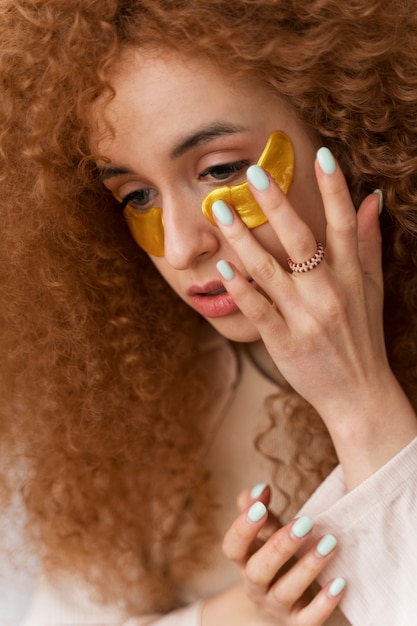 Free photo woman enjoying her beauty routine with golden eye patches