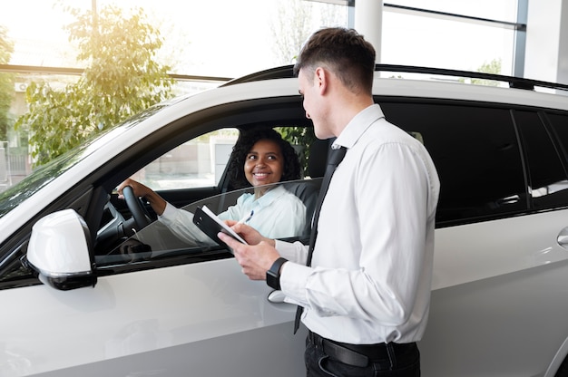 Foto gratuita donna che gode della sua indipendenza finanziaria durante l'acquisto di un'auto