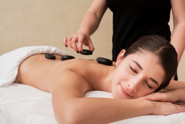 Woman enjoying hot rocks therapy at spa