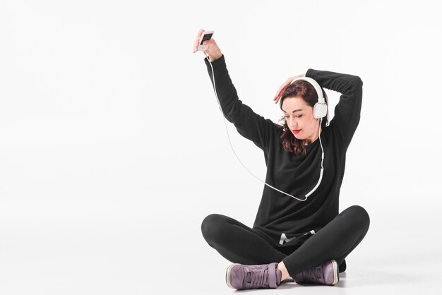 Woman enjoying music on mp3 player and dancing against white background