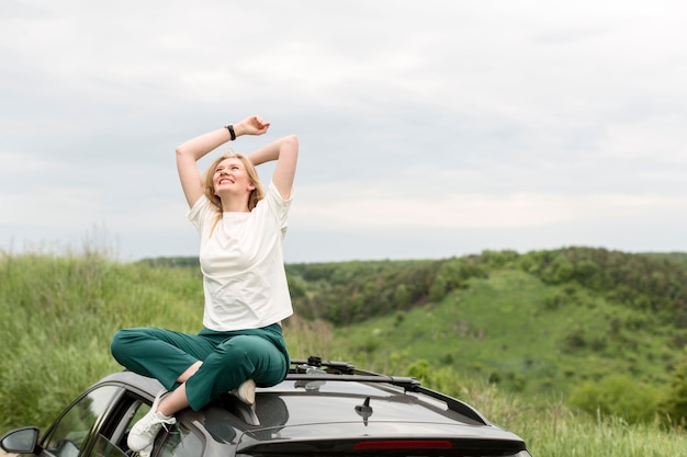 Woman enjoying nature on top of car