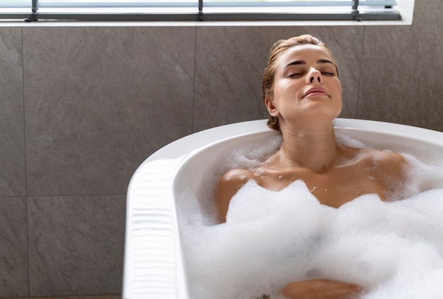 Женщина, наслаждаясь расслабляющей пенной ванной