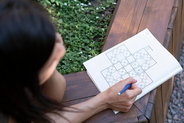 Free photo woman enjoying a sudoku game on paper by herself