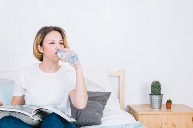 Free photo woman enjoying water while reading magazine