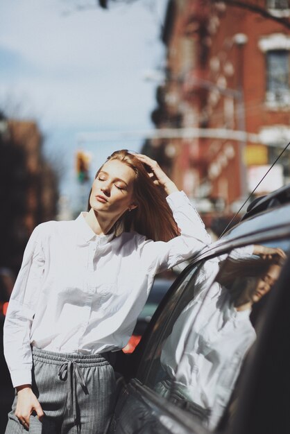 女性は、通りの車に傾いている日差しを楽しむ