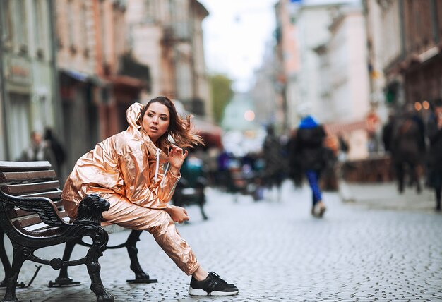 Woman enjoys the wind sitting on the bench on the street 