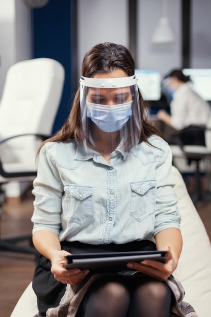 Woman entrepreneur wearing face mask against covid19 as safety precaution. Multiethnic business team working respecting social distance during global pandemic with covid-19.