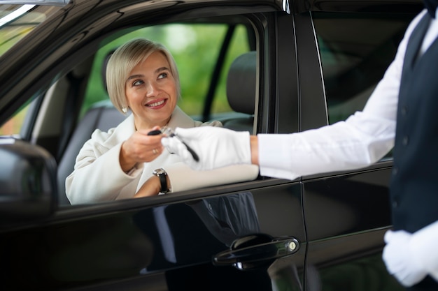 駐車係員と車のキーを交換する女性