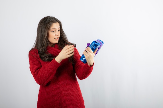 Woman excited about a Christmas gift box with purple ribbon . 