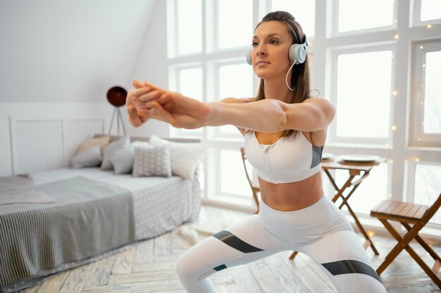 Женщина тренируется дома и слушает музыку