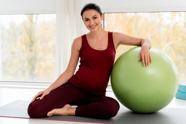 Woman exercising with fitness ball while being pregnant