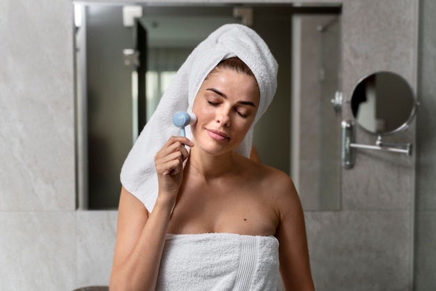 Woman exfoliating her face with a brush