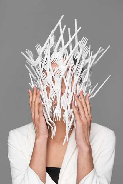 Woman face being covered in plastic tableware