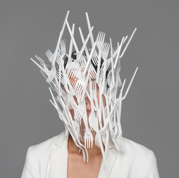 Free photo woman face being covered in white plastic tableware