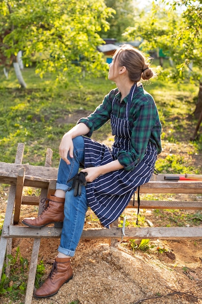 Free photo woman farmer relaxing on a fence