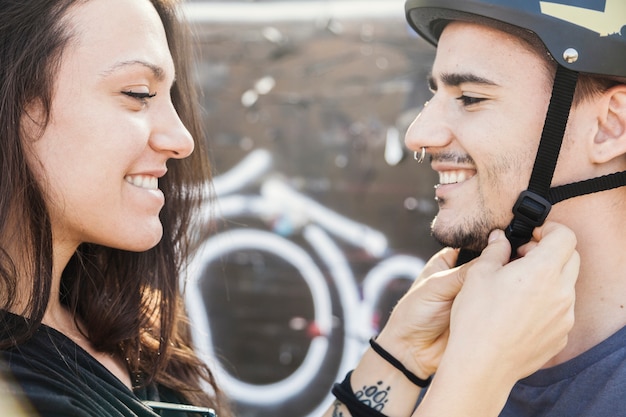 Woman fastening helmet on man